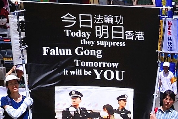Participants in a parade on the afternoon of June 23, 2013 in Hong Kong carry a banner warning that the suppression of the rights of Falun Gong practitioners in Hong Kong can spread to others. Speakers at a rally following the parade condemned Hong Kong's chief executive for being a member of the Chinese Communist Party and responsible for campaigns aimed at suppressing Falun Gong practitioners and democracy activists. (Song Xianglong/Epoch Times)