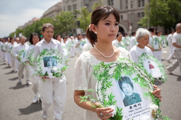 Marching Falun Gong practitioners hold photos of victims of the persecution during a parade in Washington, on July 18, 2011. (Epoch Times)