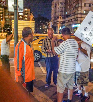 A member of the Concentric Patriotism Association hands out money to temporary workers that were holding placards attacking Falun Gong, a Chinese spiritual practice, in October 2013. (Ke-Ren/Epoch Times)
