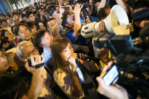 A woman who is pro-CCP speaks on a loud speaker as pro-democracy protesters boo and yell at her in the Central District of Hong Kong on Oct. 7. (Benjamin Chasteen/Epoch Times)