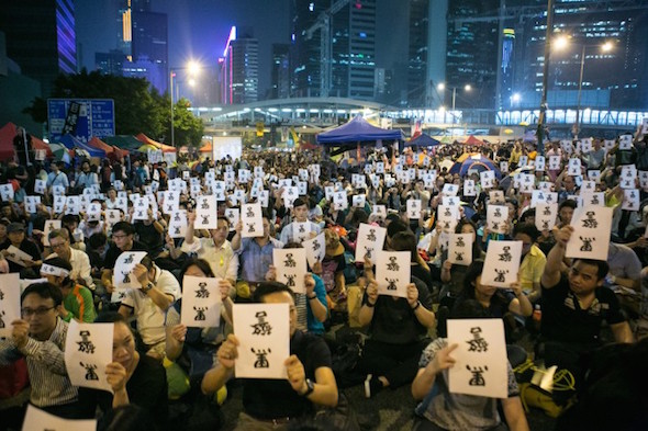Thousands of pro-democracy protesters hold signs upside down that say in Chinese “Black Police,” referring to the incident in which police beat and kicked protesters as they removed them from Lung Wo Road, on Oct. 15. (Benjamin Chasteen/Epoch Times)