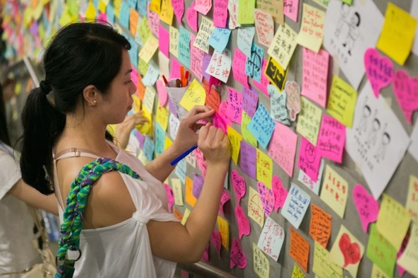 A woman leaves a note on a wall of the Legislative Counsel building in the Admiralty district of Hong Kong on October 2, 2014. (Benjamin Chasteen/Epoch Times)