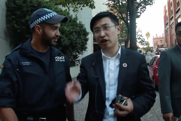This screenshot shows an unidentified Chinese man (R) who, according to witnesses, was seen giving directions to the NSW police during Chinese leader Xi Jinping's visit to Sydney on Nov 18. (Screenshot from S.G. Hughes/YouTube)